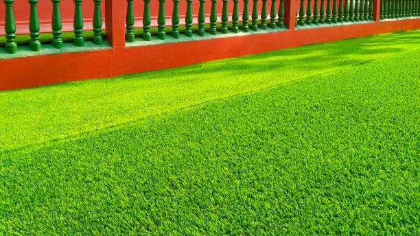 Artificial turf grass yard with vibrant green color, red border fence. -artificial turf grass
